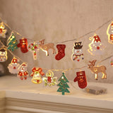 A warm white string light with colorful Christmas ornaments hangs above a white mantel beside a clear battery box.
