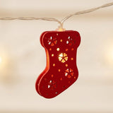 A string light close-up shows a glowing red stocking ornament with snowflake cutouts suspended from clear twisted wire against a cream background.