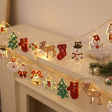 A warm white string light with colorful Christmas ornaments drapes across a white mantel beside evergreen branches and silver baubles.
