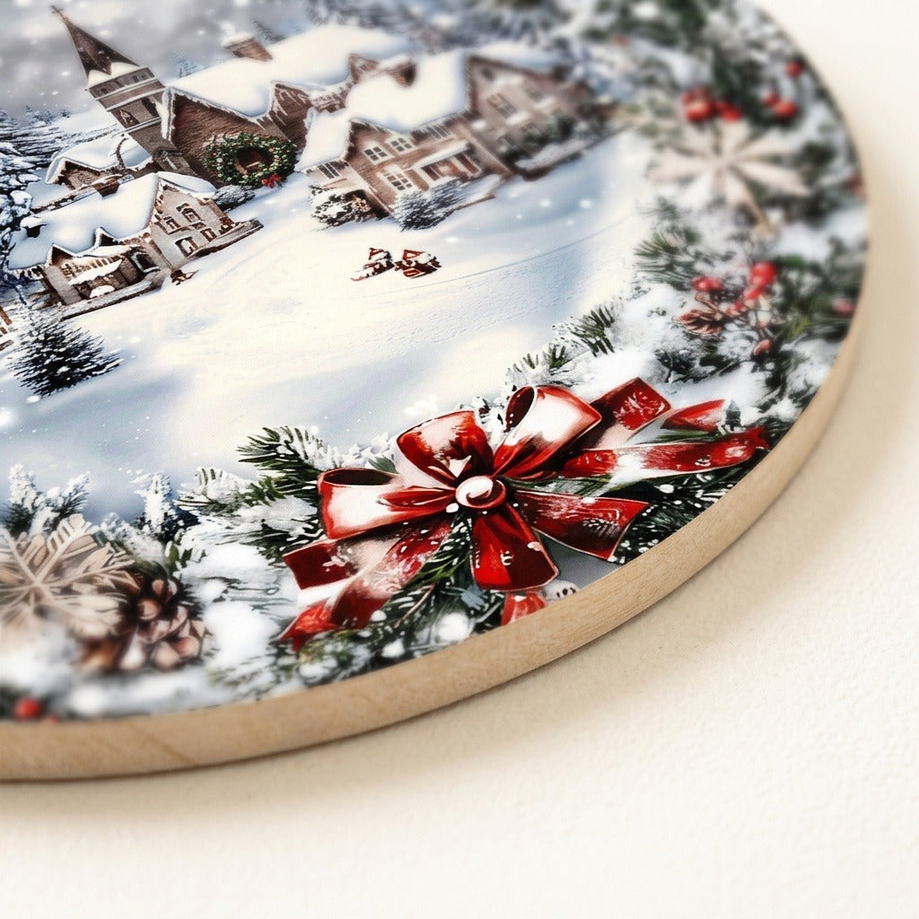 Close-up of the Christmas sign shows its tan wood edge and flat snowy village artwork with a printed red bow.