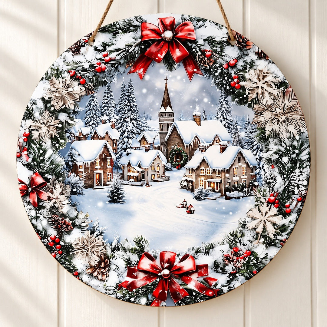 Round wood Christmas sign hangs against cream paneling, displaying flat snowy village artwork bordered by printed greenery, red bows, and snowflakes.