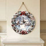Round wood Christmas sign with snowy town artwork and red bows hangs by rope on a cream wall above a white countertop.