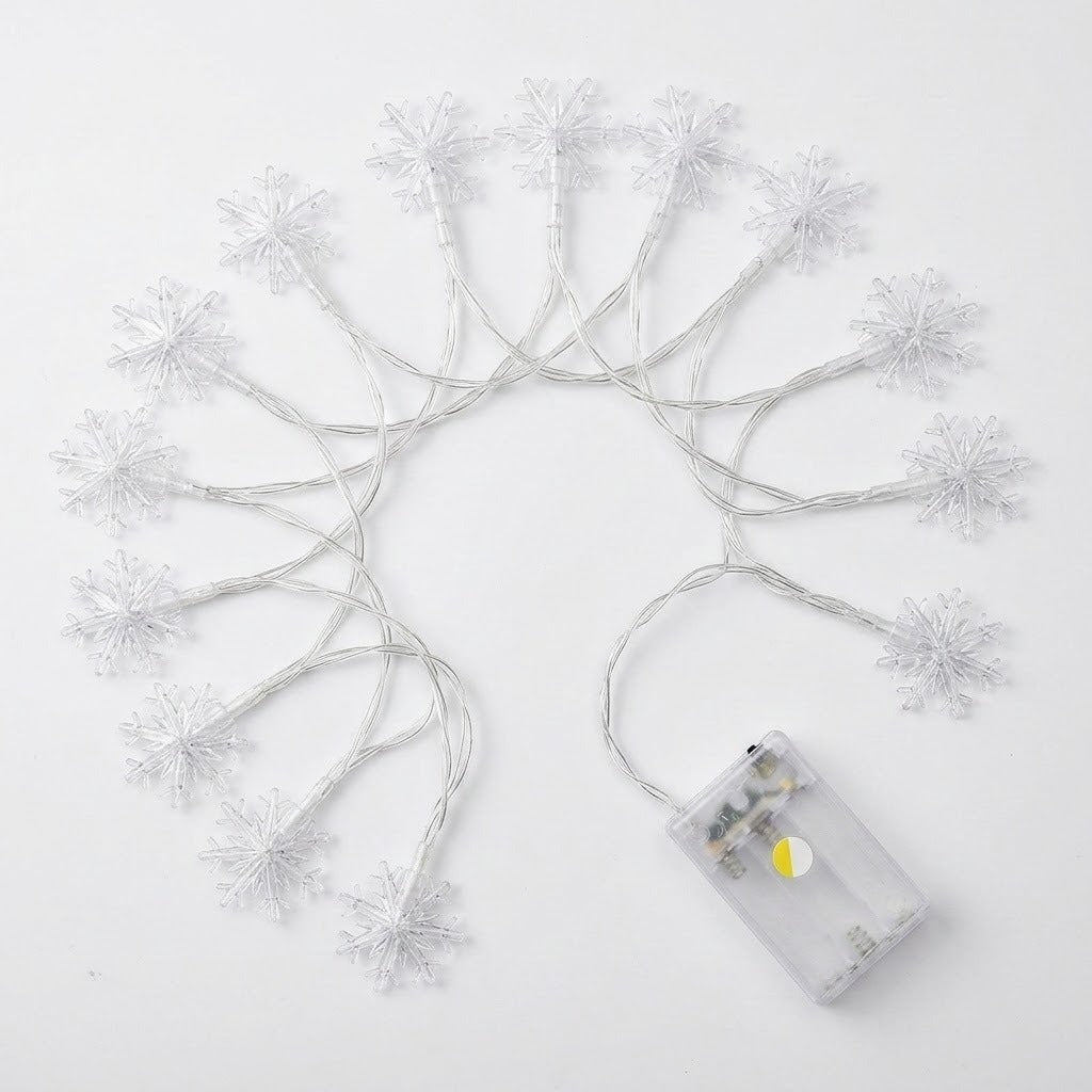 White snowflake string lights with a clear battery compartment, arranged in a semi-circle on a white background.
