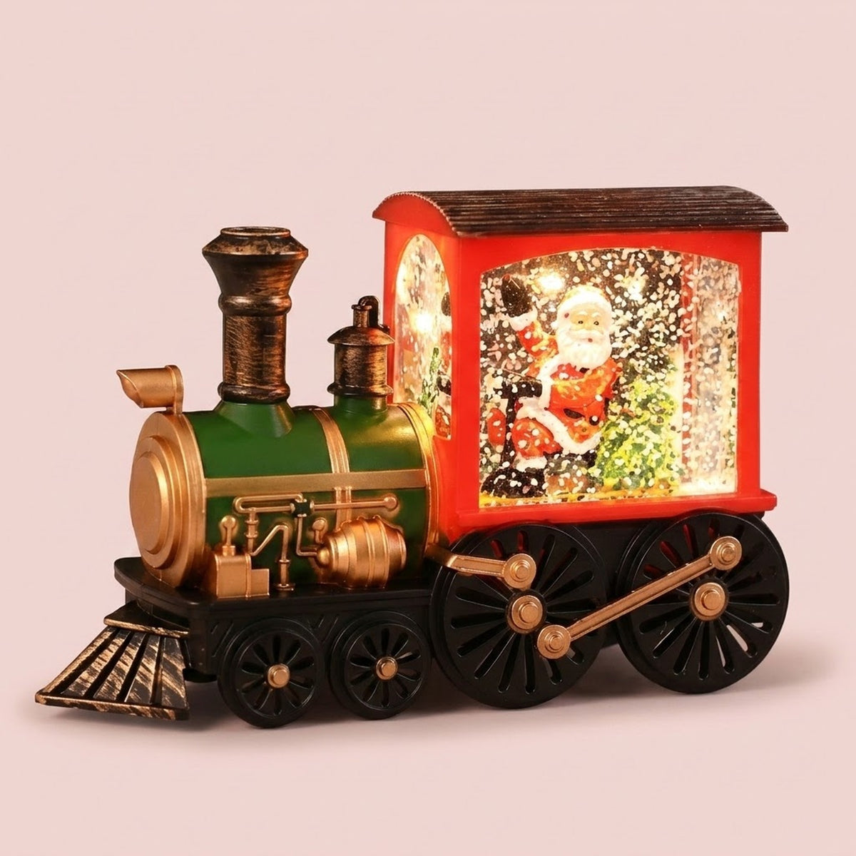 Red and green plastic Christmas train decoration displays an illuminated Santa scene with white flakes against a pale pink background.