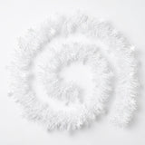 White tinsel garland with snowflake shapes lies in a loose spiral on a white background.