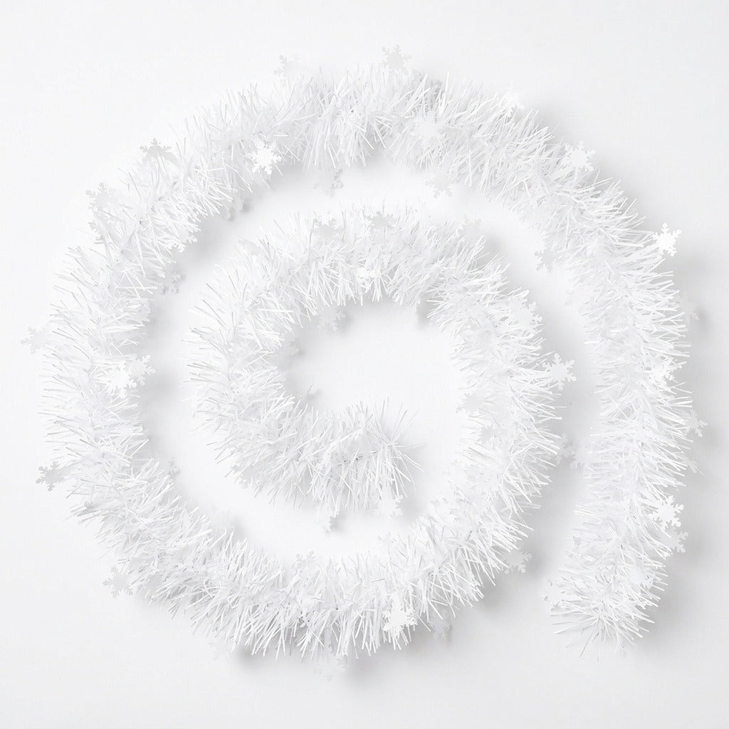 White tinsel garland with snowflake shapes lies in a loose spiral on a white background.