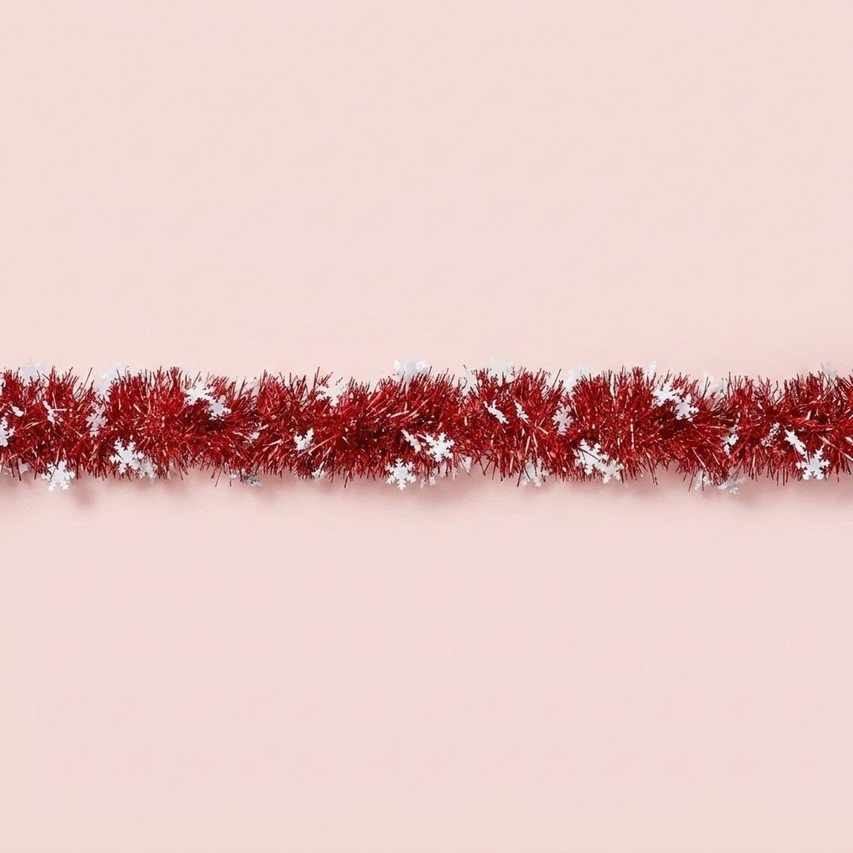 Red tinsel garland decorated with white snowflakes runs horizontally across a pale pink background.