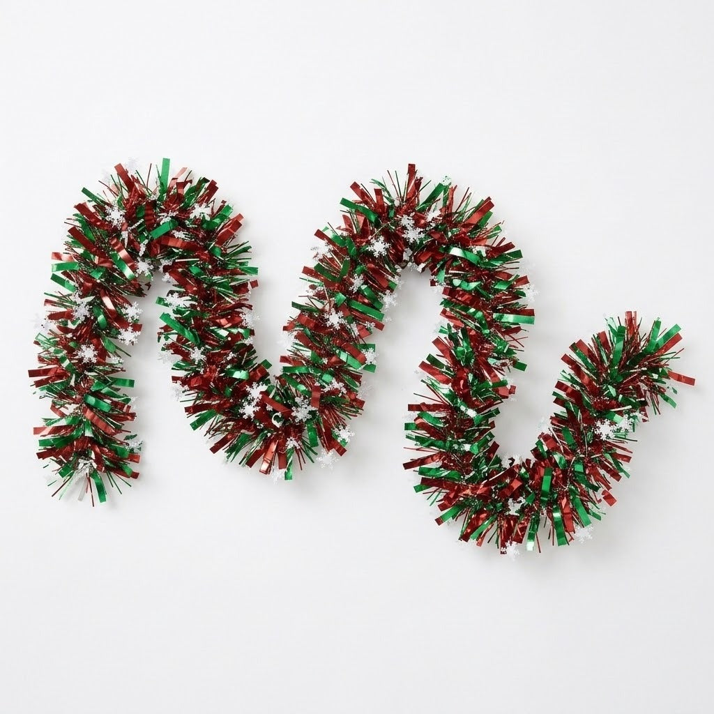 Red and green tinsel garland with white snowflakes lies in loose waves on a white background.