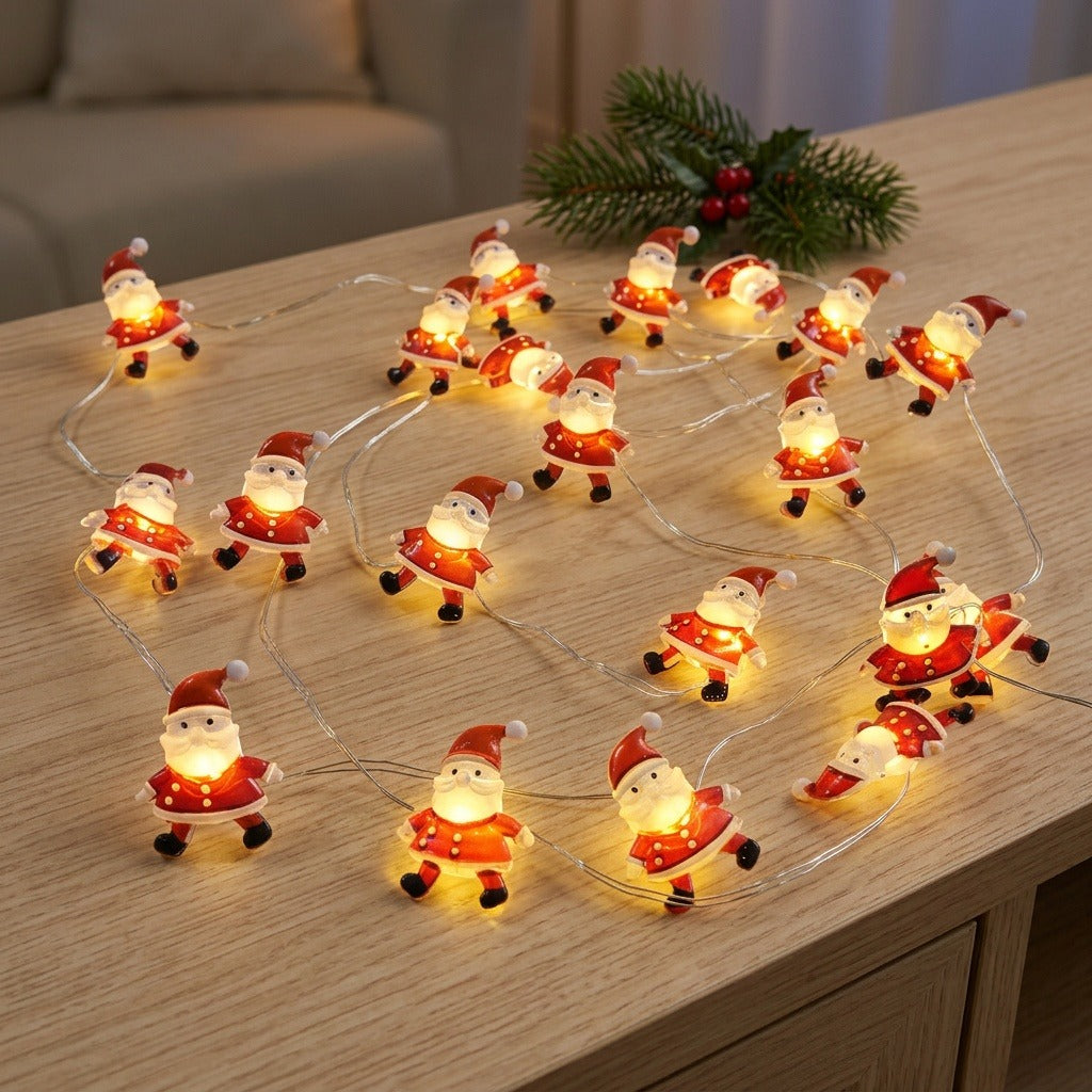 Red Santa string lights glow across a wooden tabletop beside an evergreen sprig with red berries.