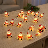 Red Santa string lights glow across a wooden tabletop beside an evergreen sprig with red berries.