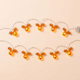 Brown antlered reindeer string lights with red noses glow yellow in two rows against a pale peach background.
