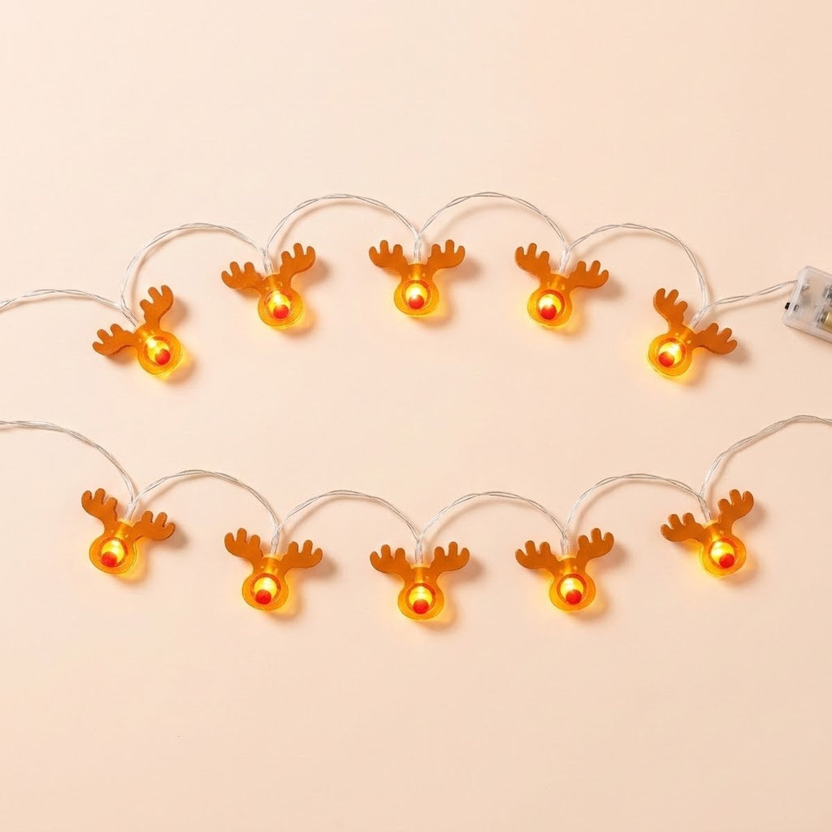 Brown antlered reindeer string lights with red noses glow yellow in two rows against a pale peach background.