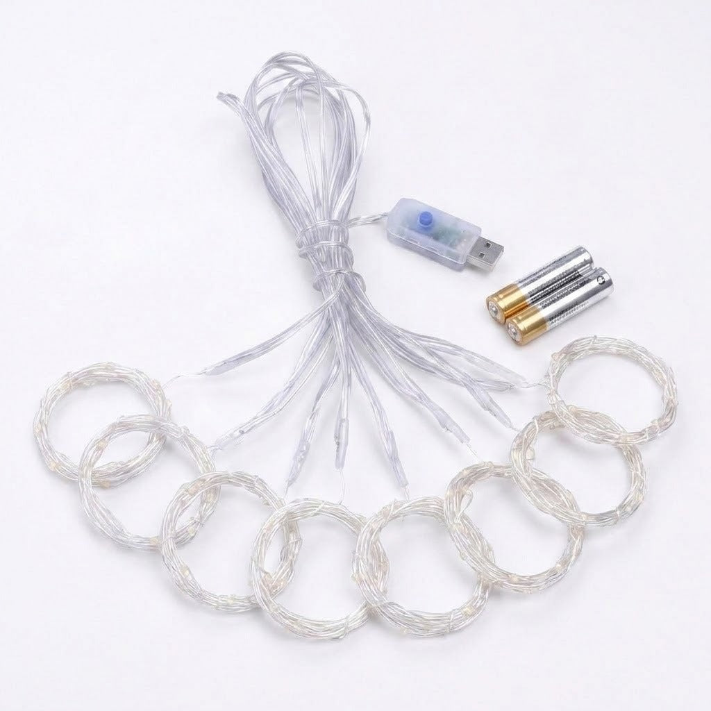 Clear curtain light strands lie coiled beside a transparent USB controller and two cylindrical batteries on a white background.