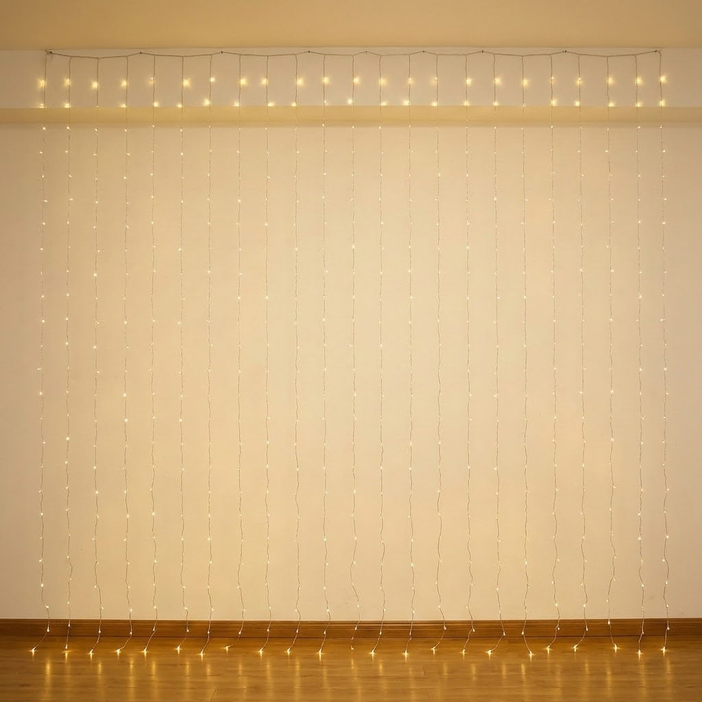 Warm white curtain lights hang against a cream wall above a brown baseboard, reflecting on the wooden floor.