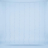 Blue curtain lights hang in spaced vertical strands from a clear cable against a pale blue background.