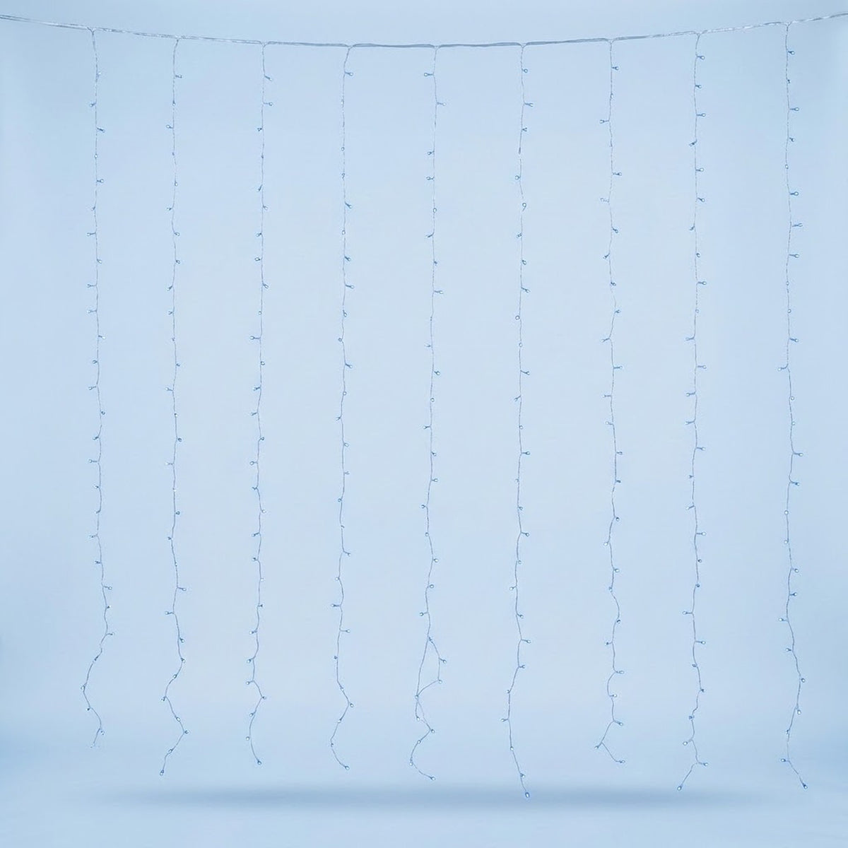Blue curtain lights hang in spaced vertical strands from a clear cable against a pale blue background.