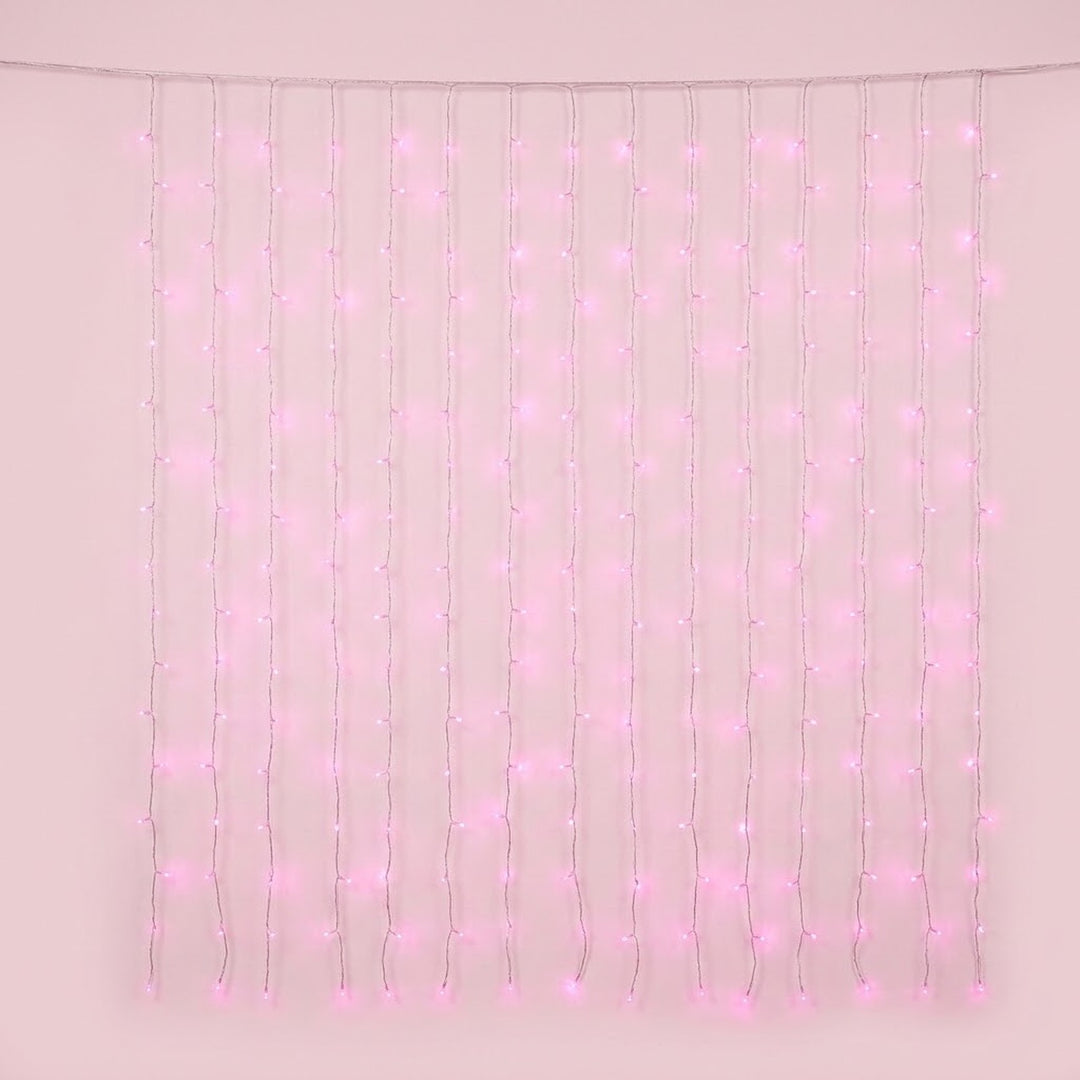Pink curtain lights hang in vertical strands from a clear horizontal cable against a pale pink background.