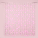 Pink curtain lights hang in vertical strands from a clear horizontal cable against a pale pink background.