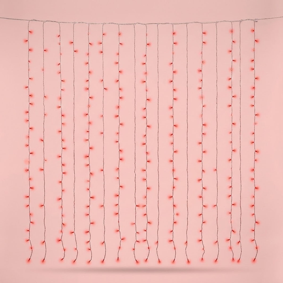 Red curtain string lights hang in vertical strands from a horizontal wire against a pale pink background.