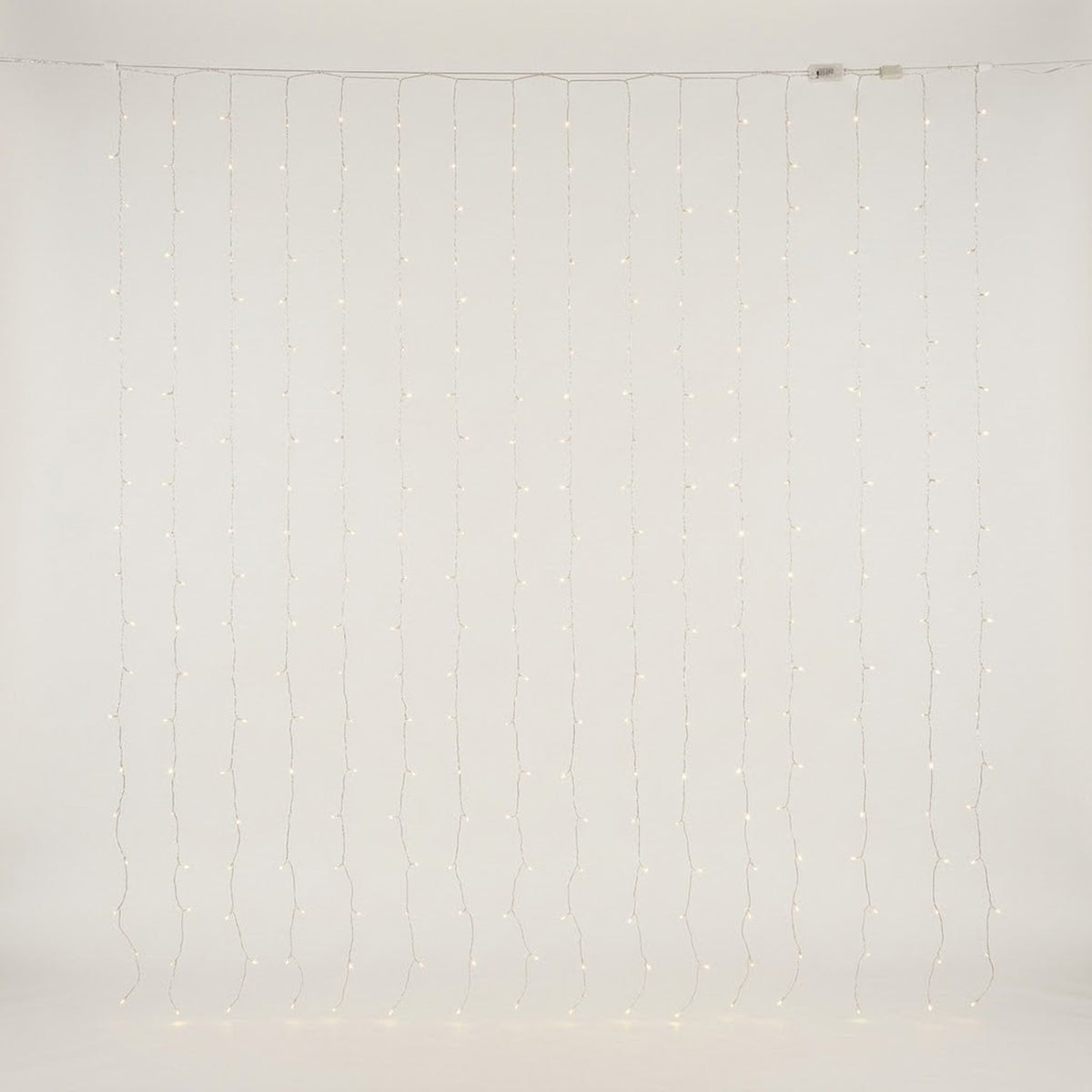 Warm white curtain lights hang in vertical strands against an off-white background, with connectors visible along the top cable.