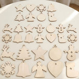 Pale wooden ornament blanks in assorted Christmas shapes and sizes lie in rows on a round white table.
