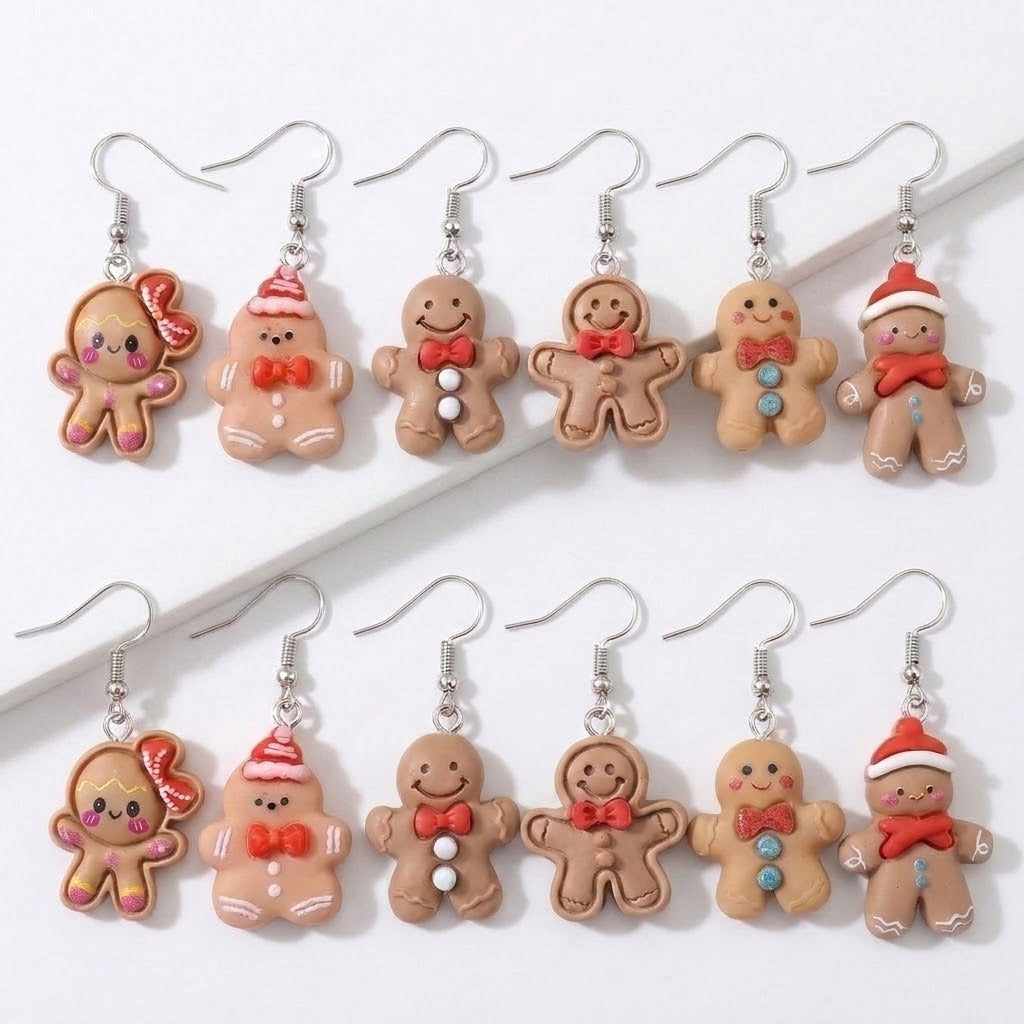 Twelve gingerbread person drop earrings with silver hooks, red bows, hats, and buttons arranged in two rows on a white stepped background.