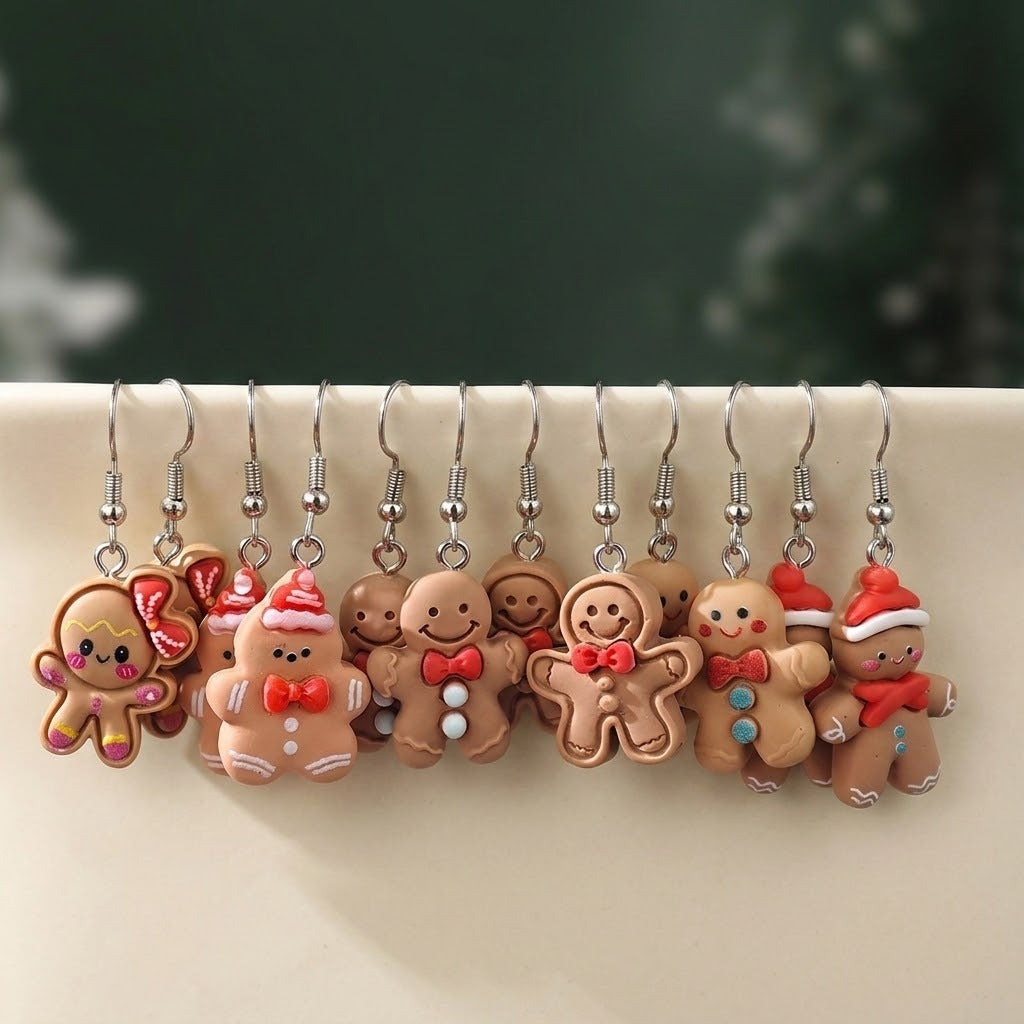 Twelve tan gingerbread drop earrings with silver hooks hang over a cream ledge against a blurred dark green background.