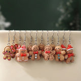 Twelve tan gingerbread drop earrings with silver hooks hang over a cream ledge against a blurred dark green background.