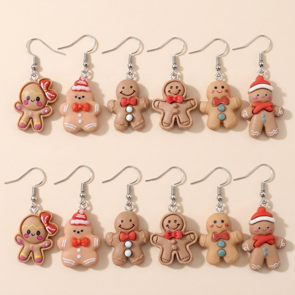 Twelve tan gingerbread drop earrings with red bows, Santa hats, and contrasting buttons lie in two rows on a cream surface.