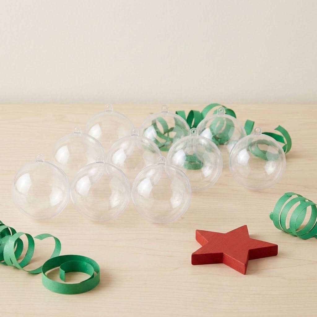 Clear plastic fillable ornaments sit on pale wood beside green paper curls and a red star.