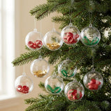 Clear plastic fillable ornaments containing red and green curls or gold stars hang from evergreen branches beside a window.