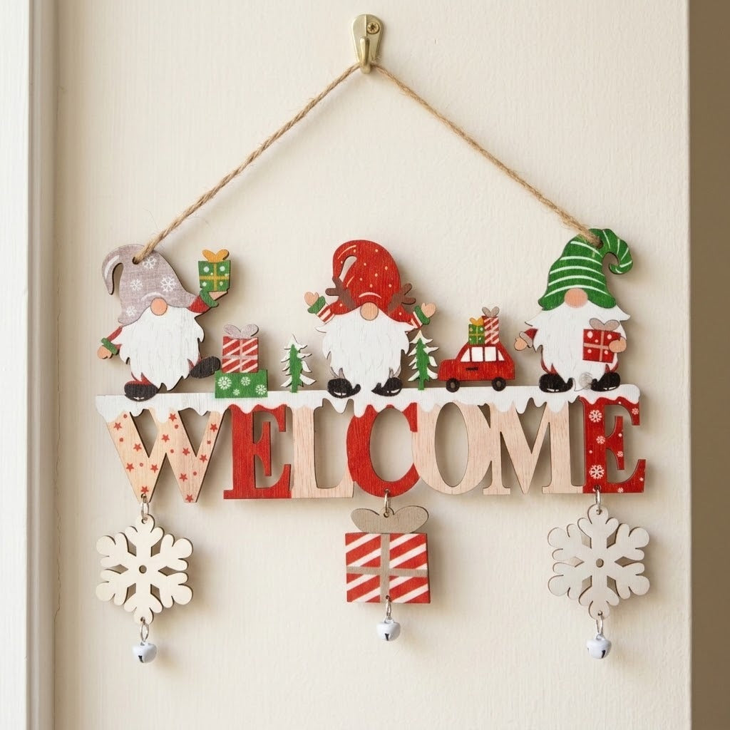 Wooden Christmas ornament with colorful gnomes, WELCOME letters, snowflakes, and bells hangs by twine from a brass-colored hook on a cream door.