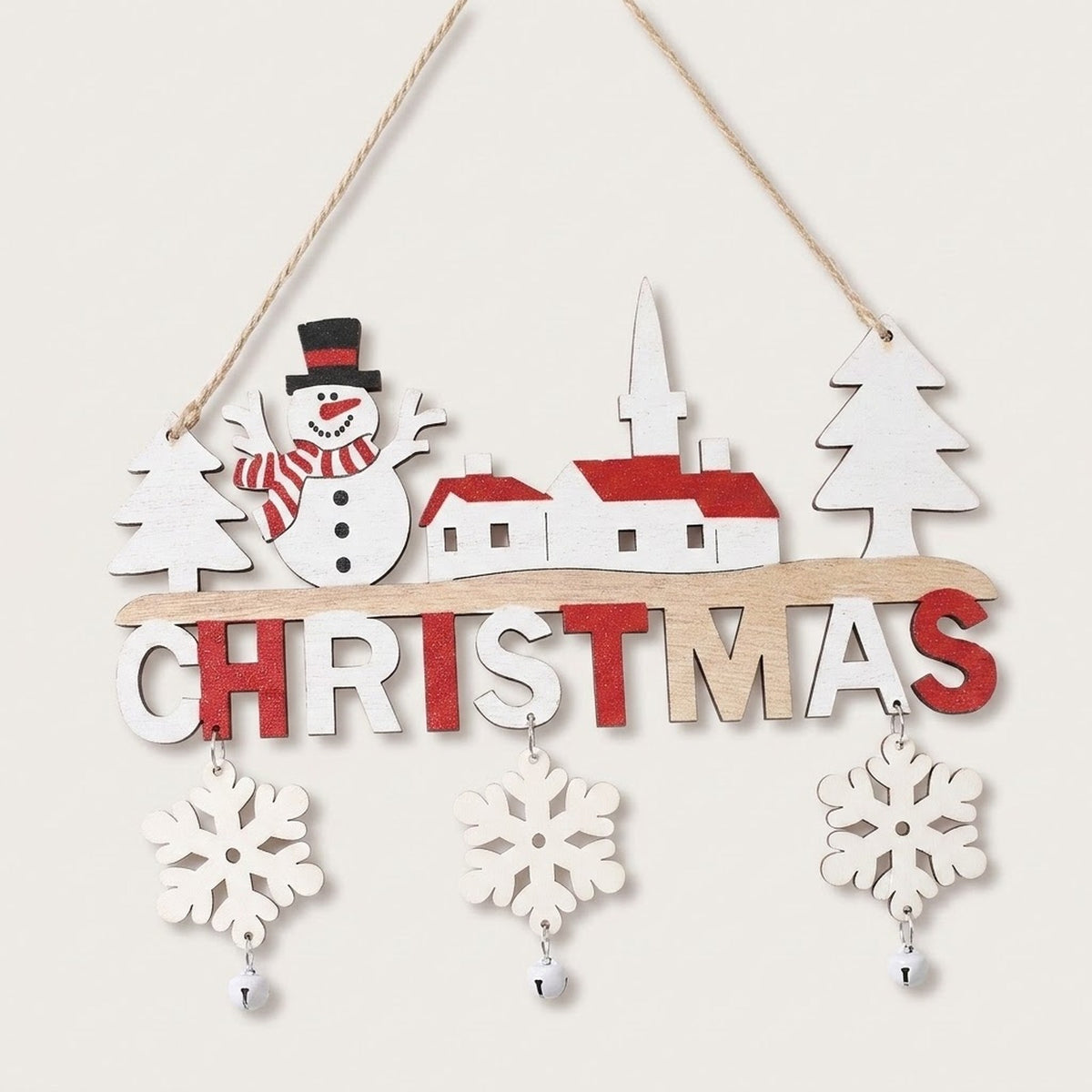 Wooden Christmas ornament featuring a snowman, white village buildings with red roofs, dangling snowflakes, and silver bells hangs against an off-white background.