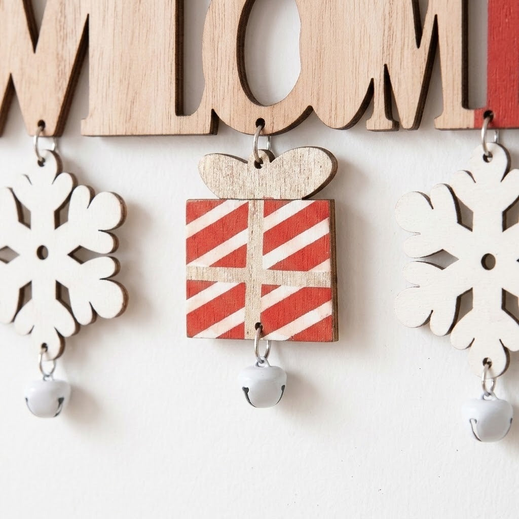 Wooden Christmas ornament detail shows white snowflakes and a red striped gift dangling above silver bells against a white background.