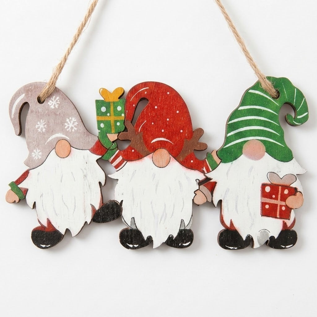 Wooden Christmas ornament features three white-bearded gnomes wearing gray, red, and green hats, suspended by twine against a white background.