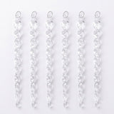 Six clear acrylic Christmas ornaments shaped like twisted icicles lie side by side with silver hanging loops against a white background.