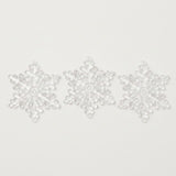 Three clear acrylic snowflake Christmas ornaments with six branching points sit side by side on a white background.