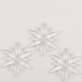Three clear acrylic starburst Christmas ornaments with long pointed rays form a triangular arrangement on a white background.