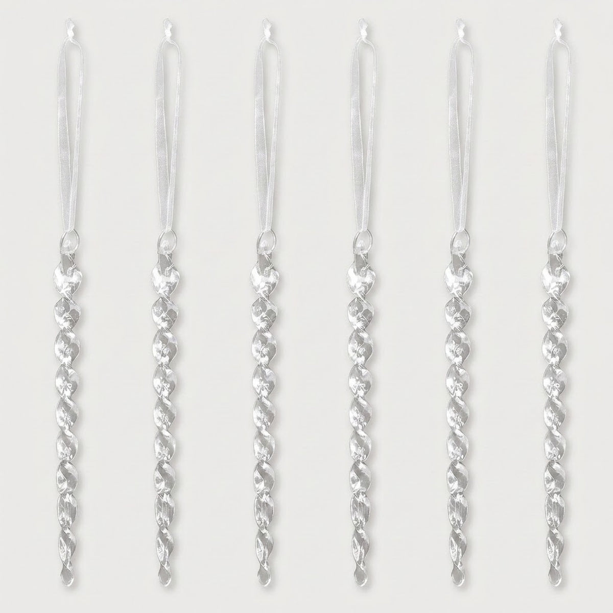 Six clear acrylic twisted icicle Christmas ornaments with white hanging ribbons are evenly spaced against a white background.