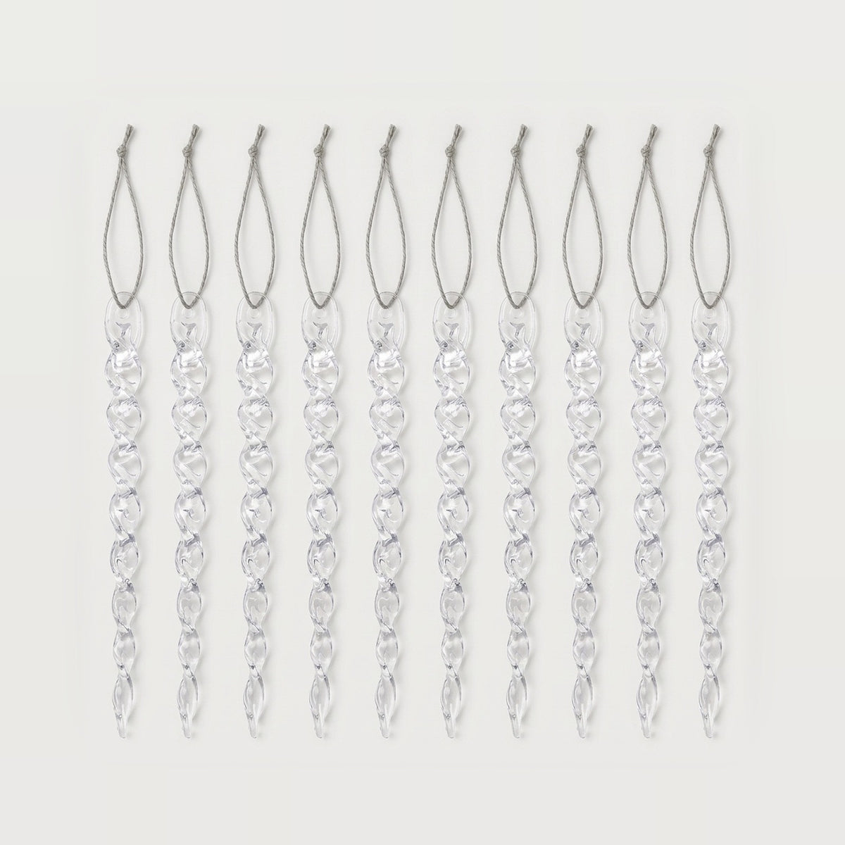 Ten clear twisted icicle ornaments with silver hanging loops form an evenly spaced row against a white background.