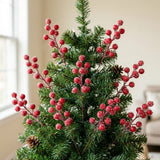 Frosted red berry picks decorate a green Christmas tree with pinecones beside a window in a beige room.