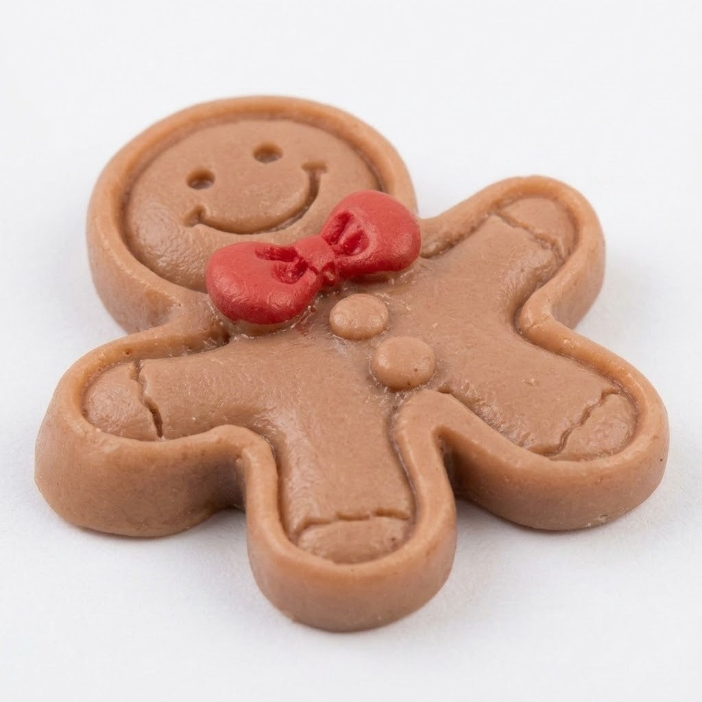 A brown resin gingerbread craft embellishment with a red bow, brown buttons, and recessed outlines rests on white in close-up.