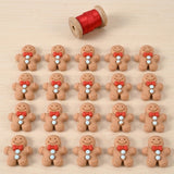 Twenty brown resin gingerbread craft embellishments with red bows and pale blue buttons form four rows on wood beneath a ribbon spool.