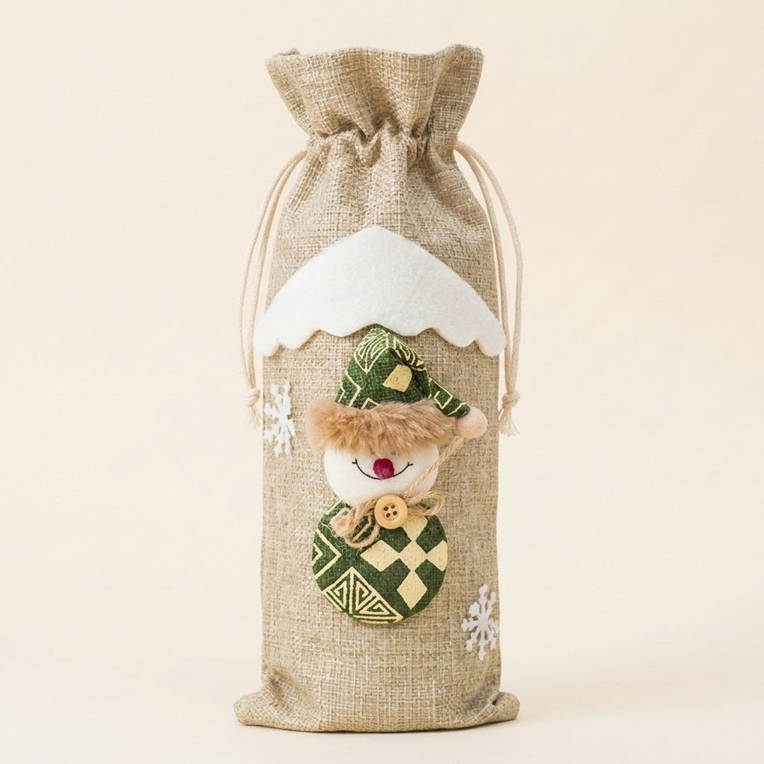 Beige linen-look drawstring wine bottle cover with a snowman appliqué in a green hat and white snowflakes against a cream background.