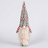 Gray knit gnome wine bottle cover with a snowflake-patterned hat, cream beard and red striped sleeves against a light gray background.