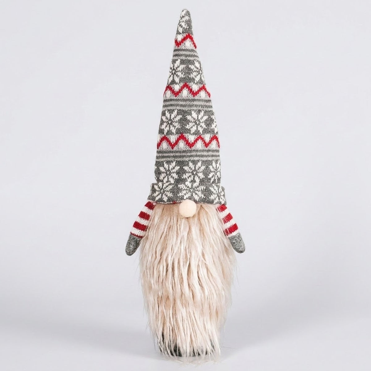 Gray knit gnome wine bottle cover with a snowflake-patterned hat, cream beard and red striped sleeves against a light gray background.