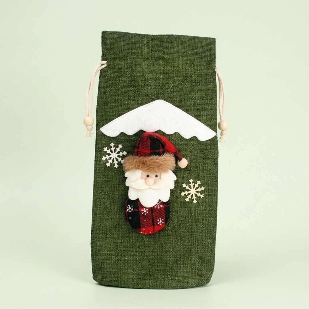 Green textured drawstring wine bottle cover with a Santa appliqué, white snowflakes and snowy roof trim against a pale green background.