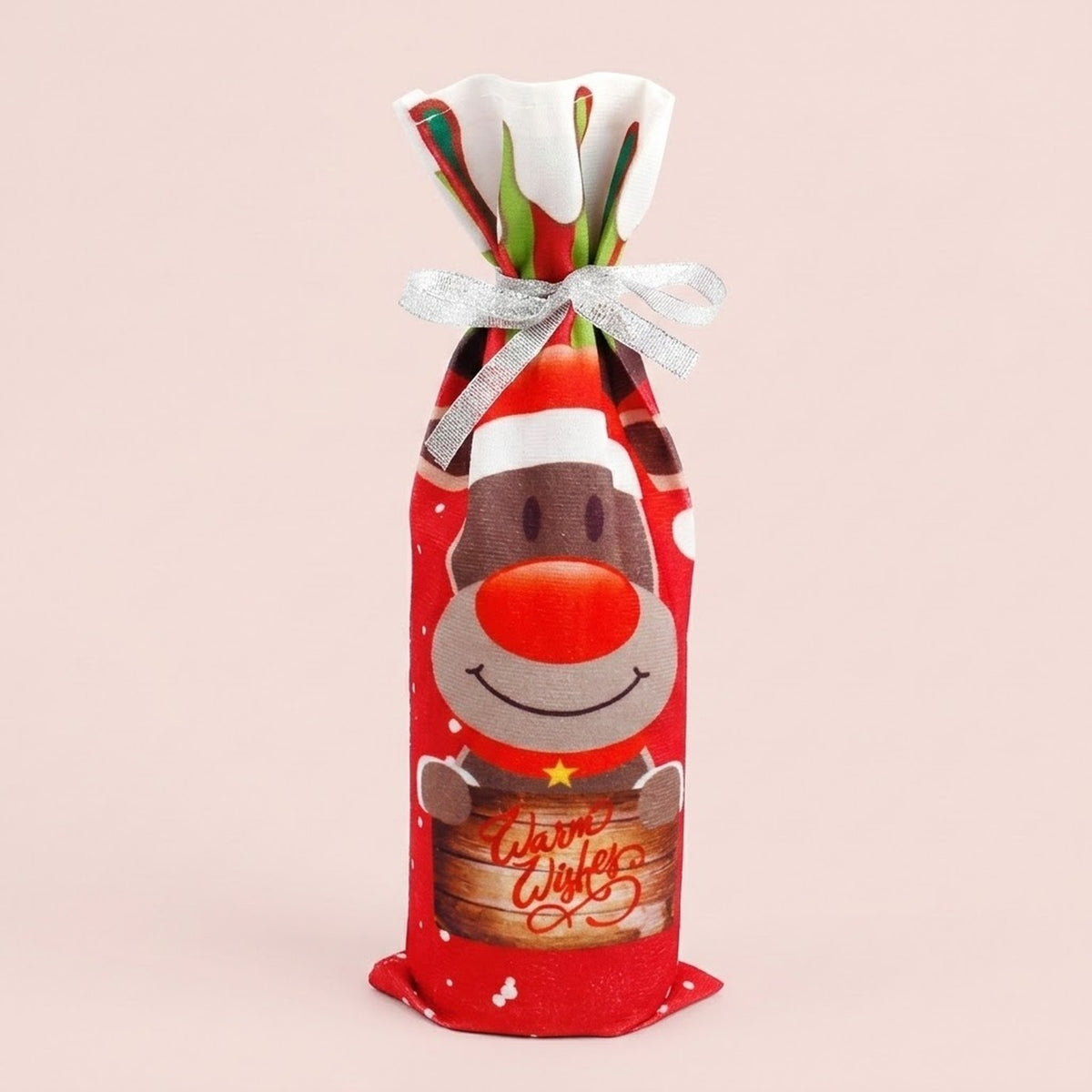 Red printed reindeer wine bottle cover tied with a silver bow shows a Warm Wishes sign against a pale pink background.