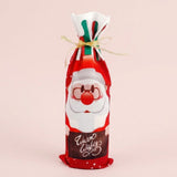 Red cloth wine bottle cover features a Santa print, Warm Wishes lettering and gold ribbon against a pale pink background.