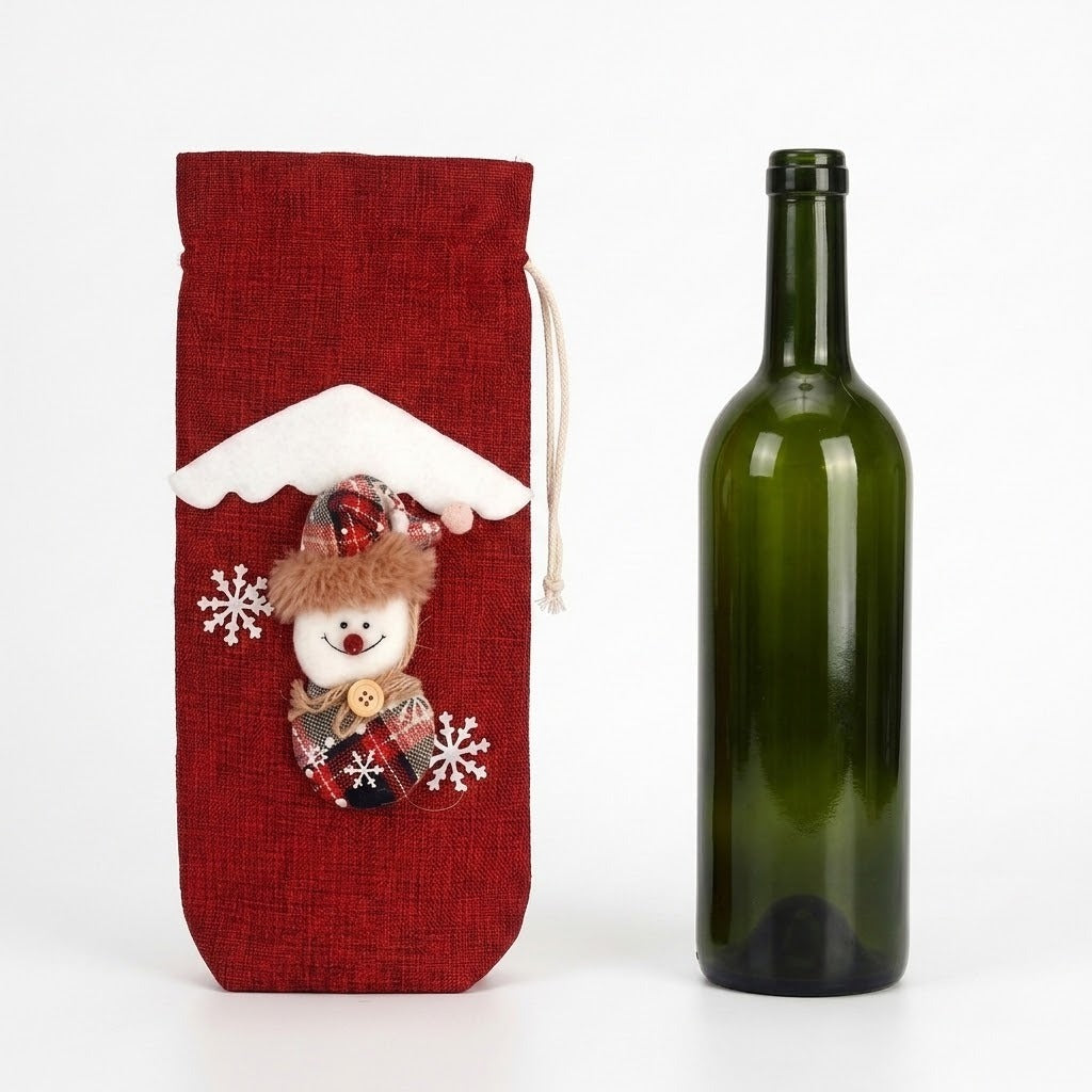 A red woven wine bottle cover with a snowman decoration stands beside an uncovered green glass bottle against a white background.
